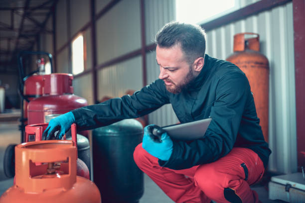 trabajador masculino examinando cilindros con tableta digital en almacenamiento de gas licuado - liquid propane gas fotografías e imágenes de stock