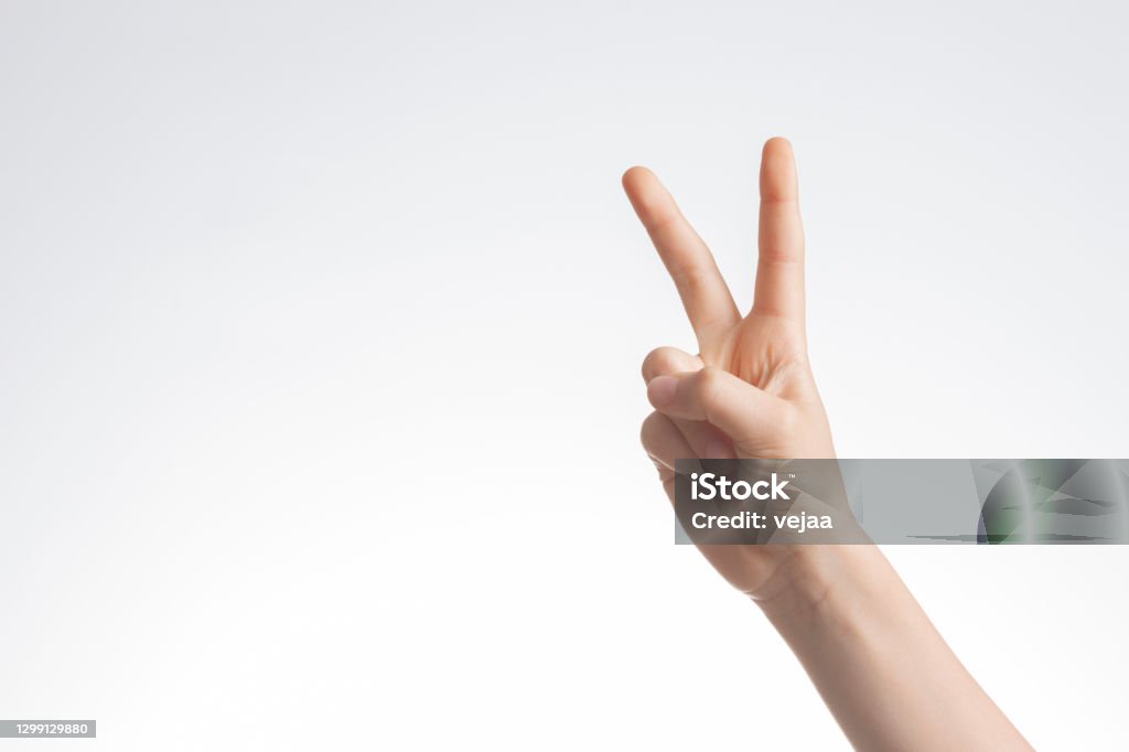 Kid hand shows victory gesture, point number two on white wall background Kid hand shows victory gesture, point number two on white wall background. Number 2 Stock Photo