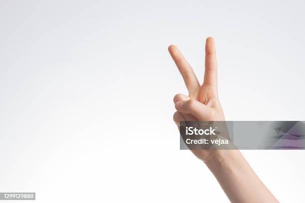 Kid Hand Shows Victory Gesture Point Number Two On White Wall Background Stock Photo - Download Image Now