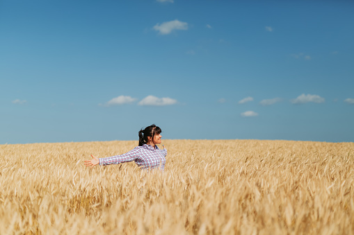Joyful mature woman with open arms in the middle of a grain field in Mallorca