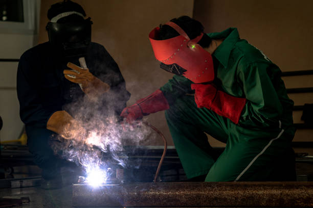 istock Workers weld metal with a arc welding machine at industrial facility. 1299131034