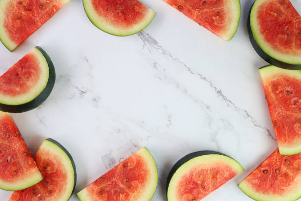 istock Close-up image of watermelon slices / chunks frame, cut into semi-circles, grey and white marble effect background, copy space, elevated view 1299131718
