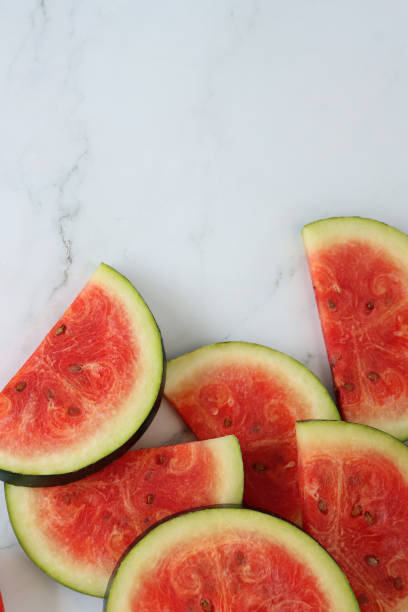 istock Image of watermelon slices / chunks pile, cut into semi-circles, grey and white marble effect background, copy space, elevated view 1299131741