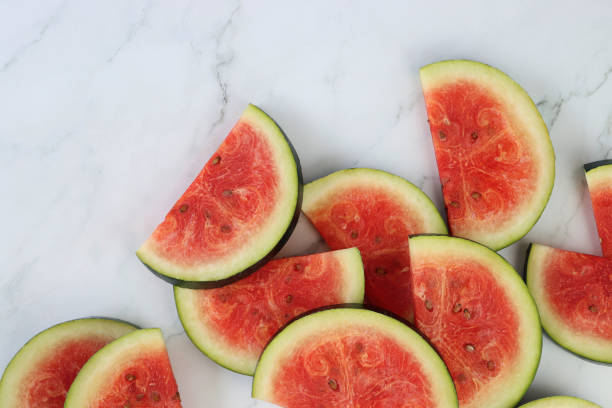 istock Close-up image of watermelon slices / chunks pile, cut into semi-circles, grey and white marble effect background, copy space, elevated view 1299131761