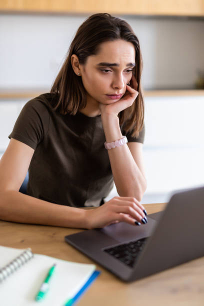 istock Smiling young woman using laptop in the kitchen at home. Working from home in quarantine lockdown. 1299131784