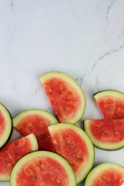 istock Image of watermelon slices / chunks pile, cut into semi-circles, grey and white marble effect background, copy space, elevated view 1299131793