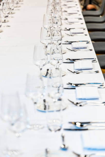 istock Long table with white tablecloth full of tableware prepared for lunch 1299131824