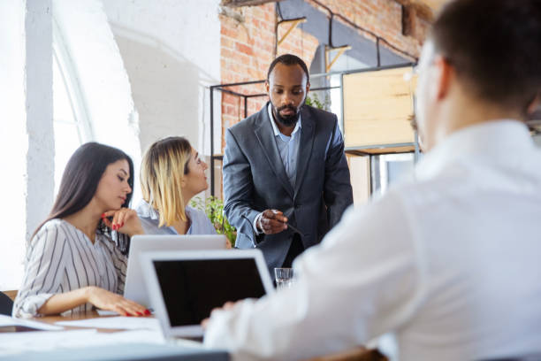 istock Diverse group of co-workers having casual discussion in office. Executives during friendly discussion, month reporting, creative meeting 1299132948