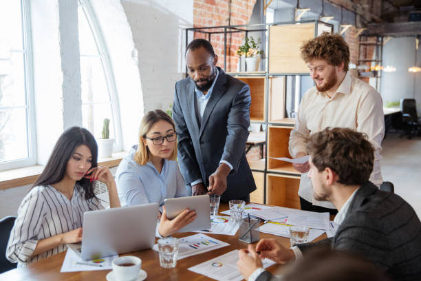 istock Diverse group of co-workers having casual discussion in office. Executives during friendly discussion, month reporting, creative meeting 1299132954