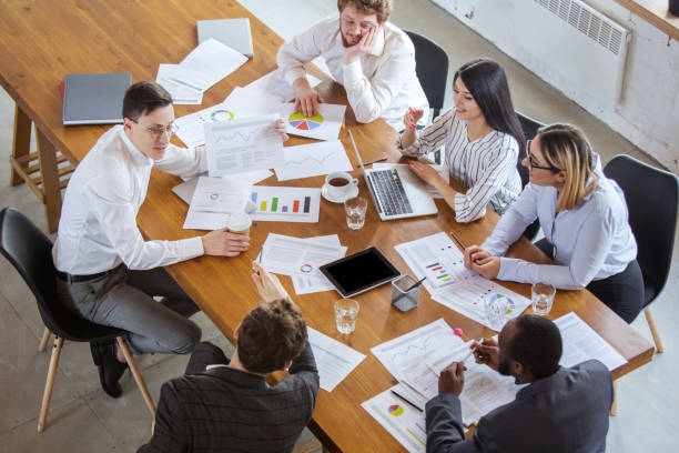 istock Diverse group of co-workers having casual discussion in office. Executives during friendly discussion, month reporting, creative meeting. Top view. 1299132963