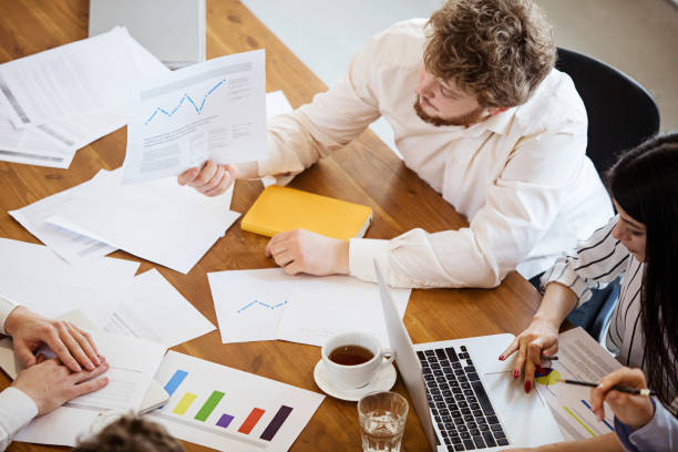 istock Diverse group of co-workers having casual discussion in office. Executives during friendly discussion, month reporting, creative meeting. Top view. 1299132967