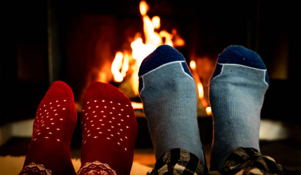 istock Feet in woolen socks in front of a warm fireplace on a cold winters evening. Shallow depth of field. 1299133250