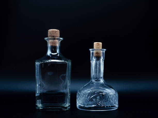 istock Empty glass carafe and empty glass bottle closed with cork caps isolated on a black background. 1299133667