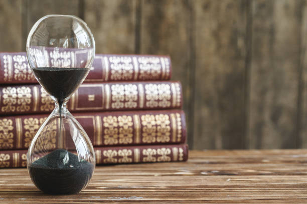 istock Vintage hourglass against a stack of old books 1299134307