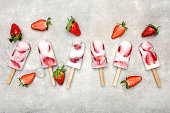 Homemade fruit popsicles with strawberries, ice lollies on sticks, top view, flat lay