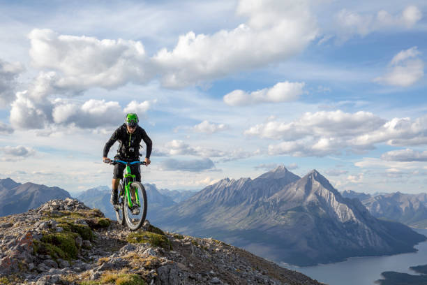 Mountain biker rides along mountain ridge in the morning Canadian Rockies visible in the distance, Bow River visible below bow river stock pictures, royalty-free photos & images