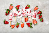 Fresh strawberry popsicle. Juicy fruit lollipops, fruity cold snack food, flat lay, top view.