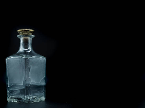istock Empty glass bottle closed with big golden round cork isolated on a black background. 1299141106
