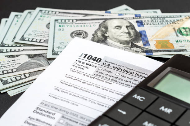 istock Tax form with calculator and money on black. 1299143903