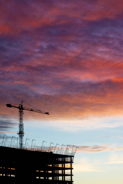istock Silhouette of a crane and a building at sunset 1299146744