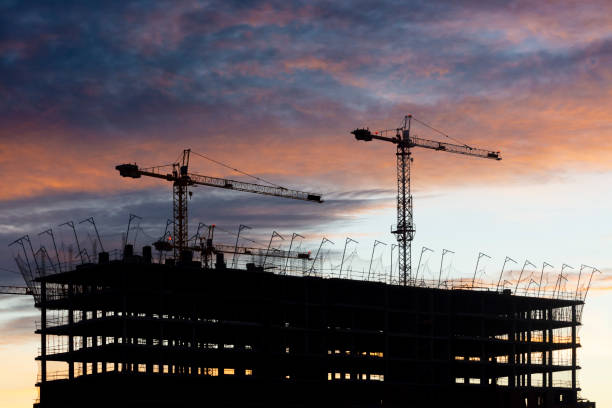 istock Backlight of two cranes and a building 1299146776