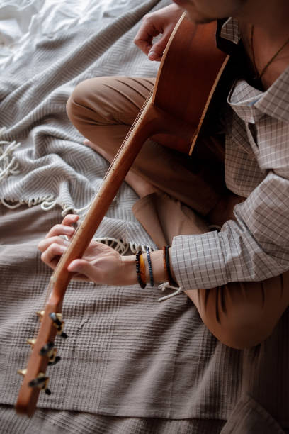 istock Man playing acoustic guitar at home on bed cozy 1299148534
