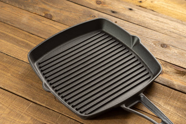 istock An empty black cast iron grill pan. Wood background. 1299149325