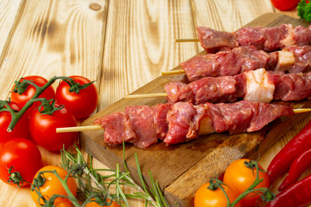 istock Raw kebab from meat on a wooden background with vegetables. 1299149471