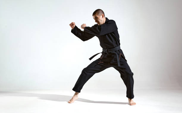 istock Fighting man in black kimono fighter shows karate technique on studio background with copy space, mix fight concept 1299149691