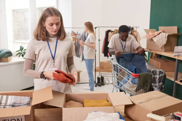 istock Group of multi-ethnic people working together in clothes charity organization sorting out and packing items for donation 1299150523