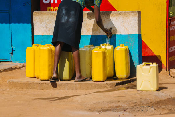 ウガンダ、アフリカの公共の水源で水缶を満タンにする女性 - plumbing supplies ストックフォトと画像
