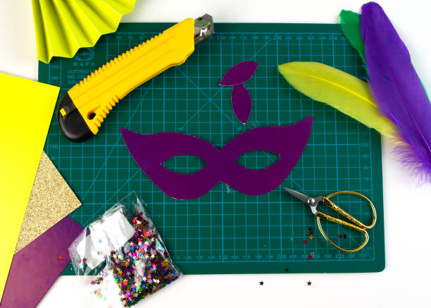 DIY colored Mardi Gras mask. Workplace with colored paper, feathers, confetti, glitter and scissors. Party preparation. Shrove Tuesday, Fat Tuesday. Flat lay