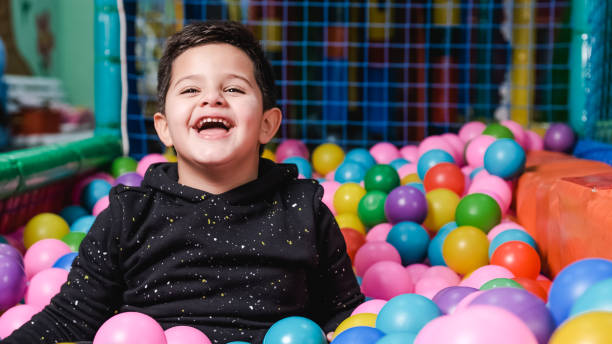 happy 5 year old boy with mask in a ball pool so happy