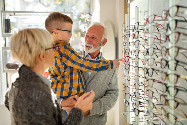 miling avô escolhendo os óculos mais adequados na loja de óptica - optometrist store retail glasses - fotografias e filmes do acervo