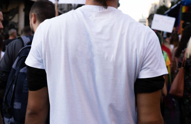 Young Protesters The rear view of people marching on the street in Belgrade. Close up of a man's back with a place for copy space on his white t-shirts. anonymous activist network stock pictures, royalty-free photos & images