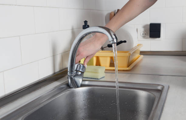istock Woman opens a faucet in the kitchen. 1299156061