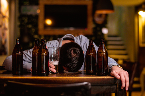 Young drunk man sleeping on bar counter