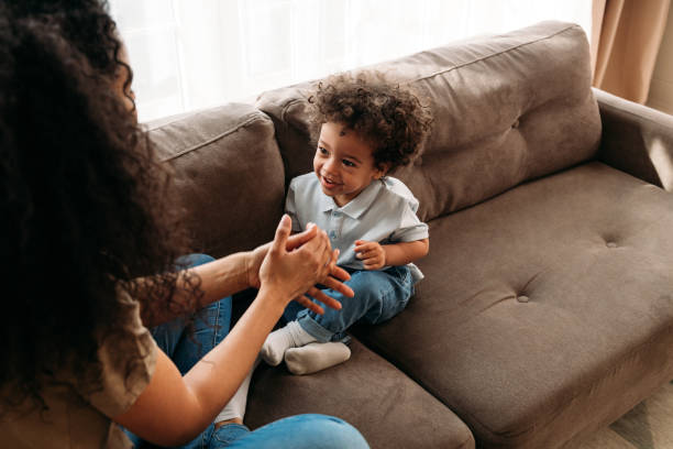 istock Son and mother sitting on a sofa in living room and playing 1299157371