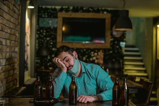 Young drunk man sleeping on bar counter