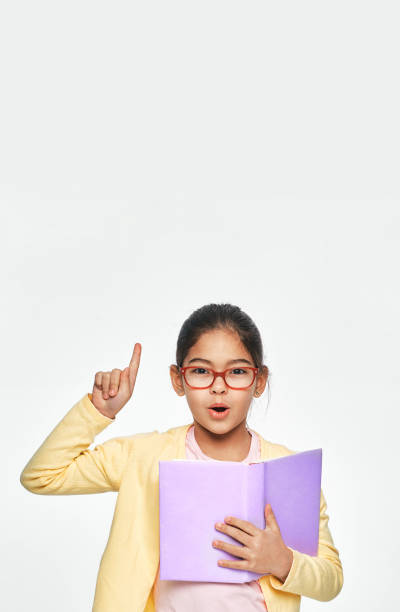 istock This is a good idea. Asian child with book in hands shows index finger up, on gray background 1299158751