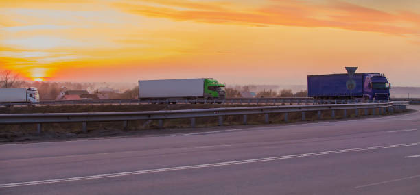 istock Trucks move at sunset on a suburban highway at a road junction 1299159115