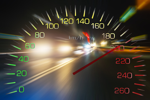 Speedometer on the background of blurry traffic of cars on the night street