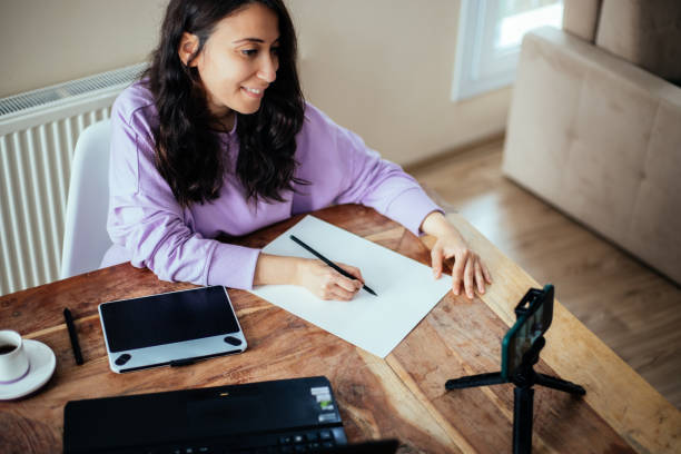 istock Woman vlogging with smartphone, drawing on the paper 1299160086