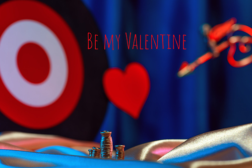 Small golden cupid marks his target with an arrow at the heart, valentine's day concept