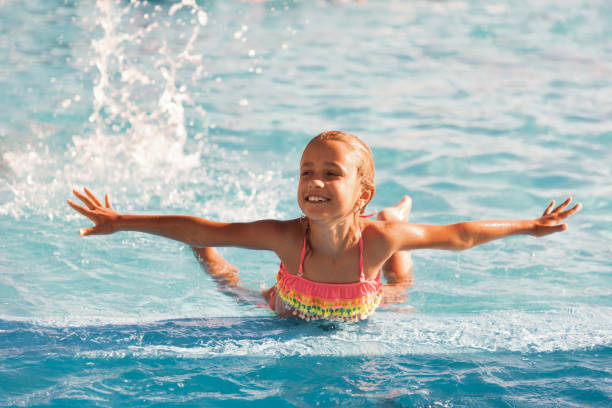 istock Cheerful girl playing in a pool and looking smiling at the camera 1299162769