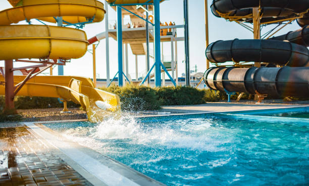 An woman descended from a slide into a pool with transparent water stock photo