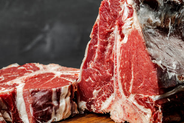 istock Raw T-bone steak cooking on stone dark table. 1299163951