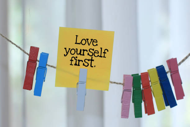 love yourself first. positive words for mental health support concept with paper note hanging on rope. - self love imagens e fotografias de stock