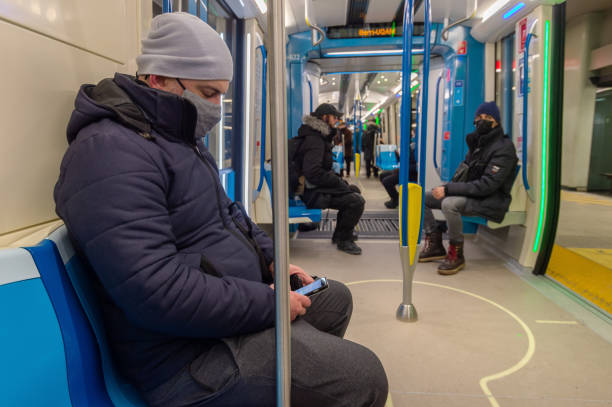 Passenger sitting in subway train, wearing face mask to protect from Covid-19 Montreal, CA - 24 January 2021: Passenger sitting in subway train, wearing face mask to protect from Covid-19 montreal underground city stock pictures, royalty-free photos & images
