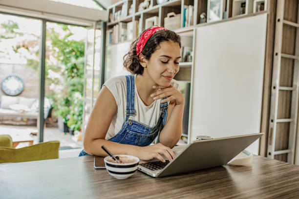 istock Young woman is using laptop at home on the kitchen counter 1299172082